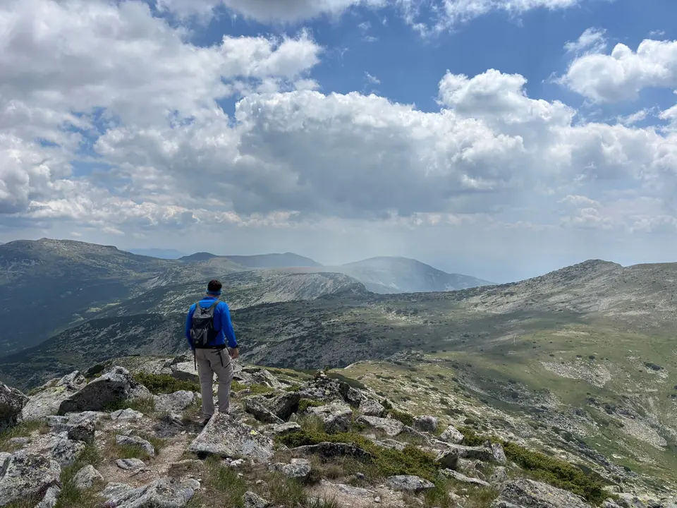 Walker among rocks on the Kanarata outing, looking across Rila.